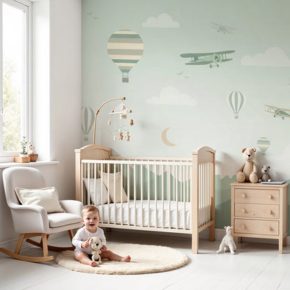 Kids-Mundo hot air balloon and biplane wall mural in a soft green nursery with a cot