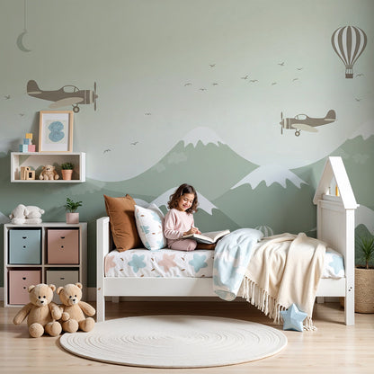 Kids-Mundo biplane and mountain wall mural in a boy's bedroom with a bed and cushions