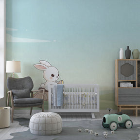 Whimsical bunny mural wallpaper with soft blue and green tones in toddler's room