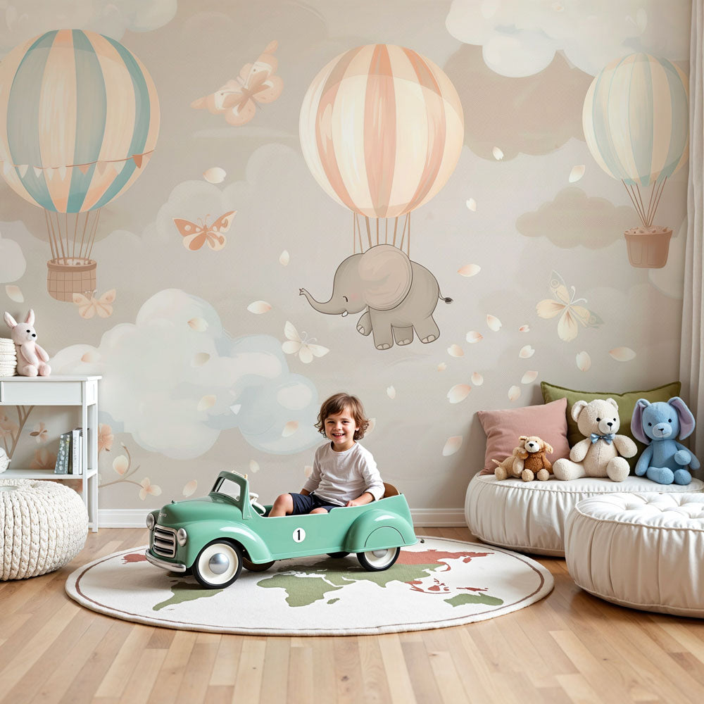 Kids-Mundo elephant and hot air balloon wall mural styled in a soft pastel nursery with cot and blossom branches.