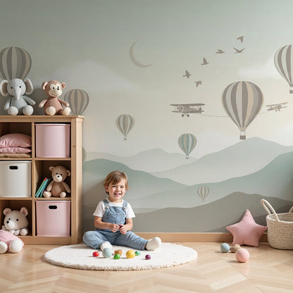 Kids-Mundo hot air balloon and biplane sky wall mural styled above a cot in a soft green nursery