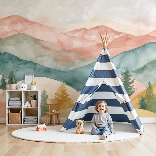 Kids-Mundo pastel watercolour mountain wall mural styled behind a cot in a soft pink nursery.