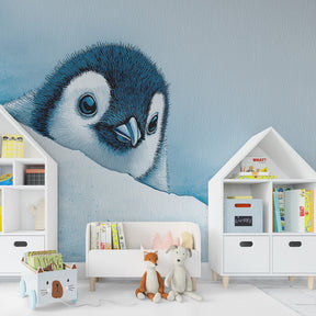 Arctic penguin mural wallpaper in cozy toddler room with light wooden furniture and blue accessories