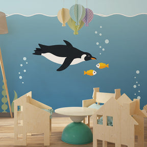 Ocean themed mural wallpaper featuring penguin and colorful fish in children's playroom