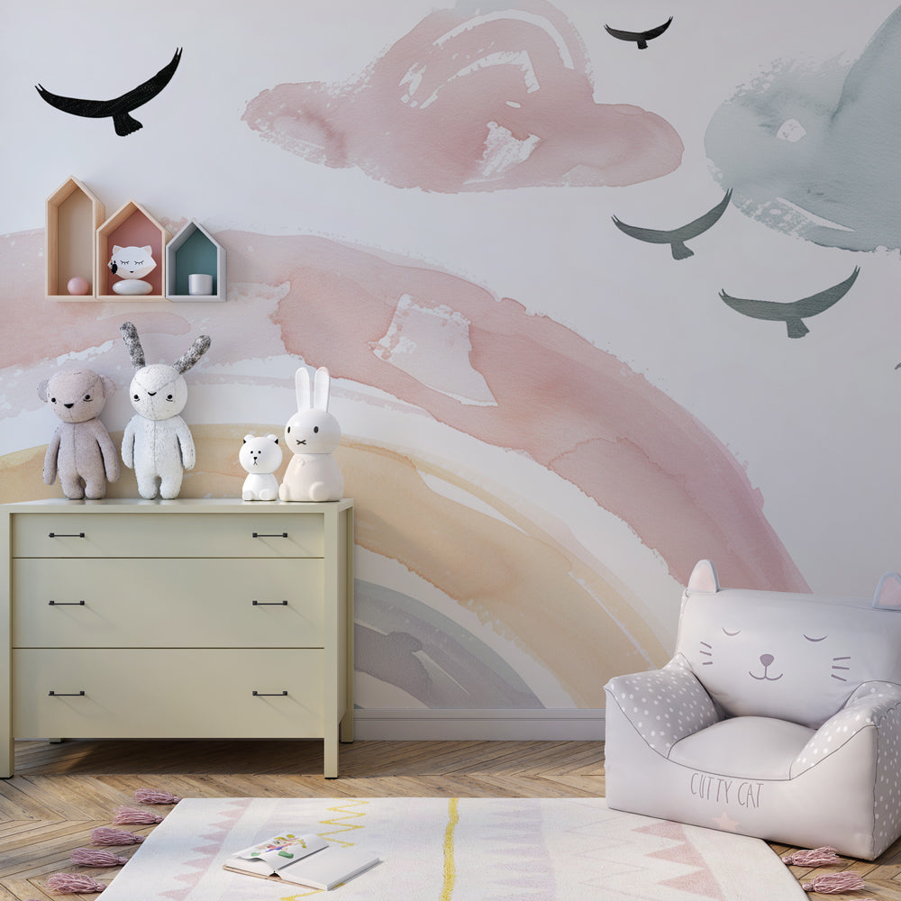 Gentle watercolor rainbow wallpaper complementing white nursery furniture and soft decor elements