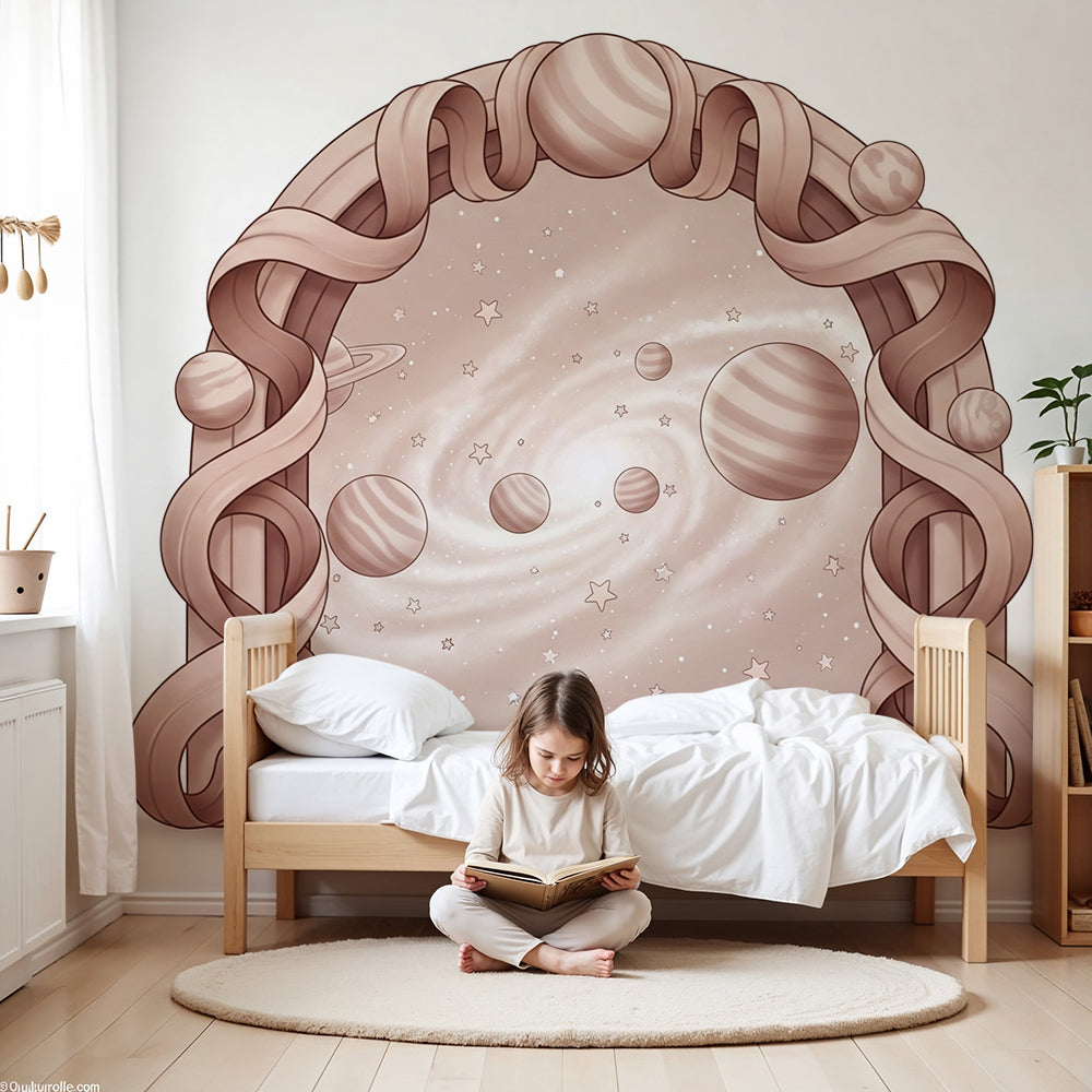 Kids-Mundo ribbon arch galaxy wall mural above a cot in a soft pink nursery.